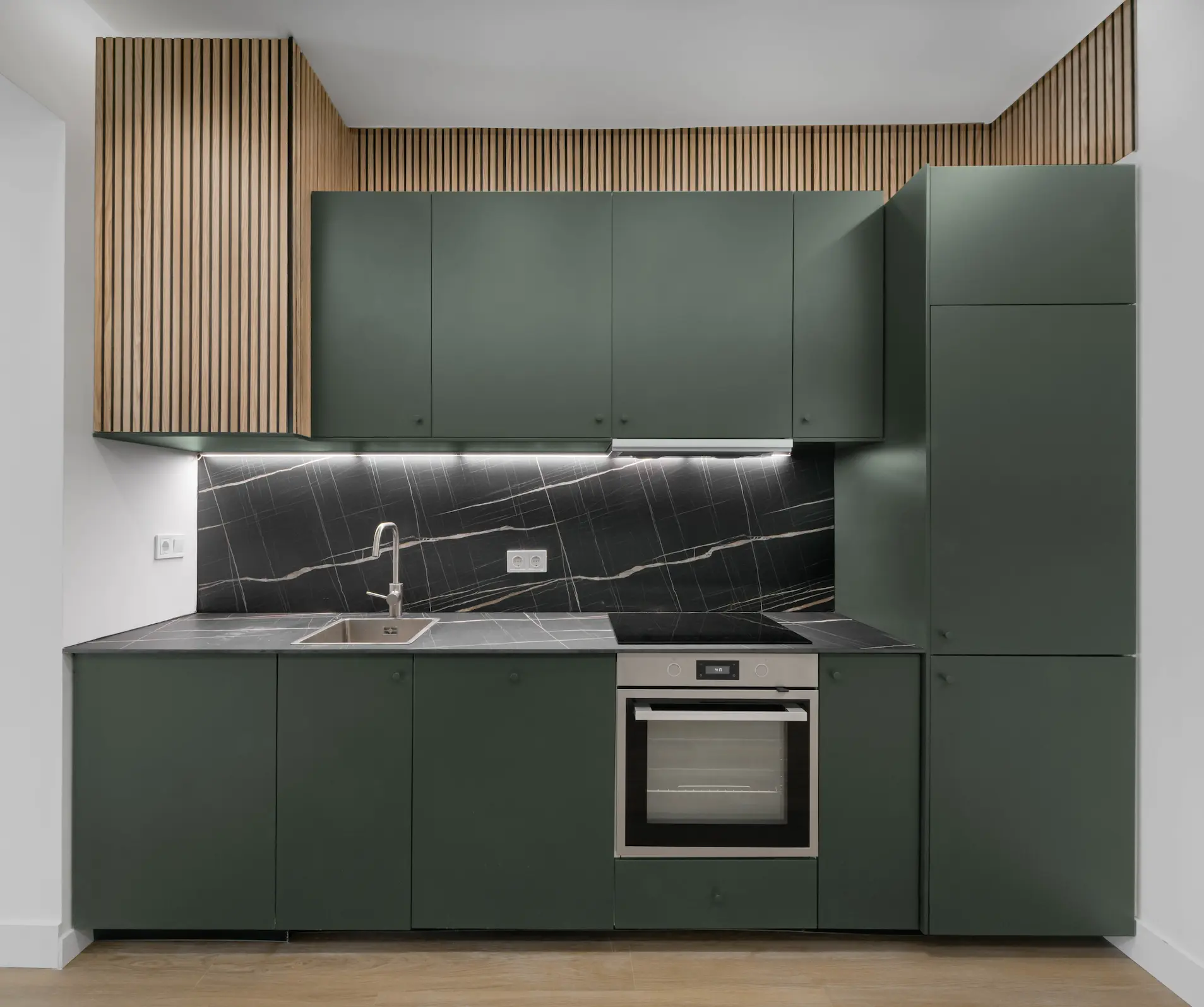 Cocina verde con panelado de madera y encimera de mármol negro