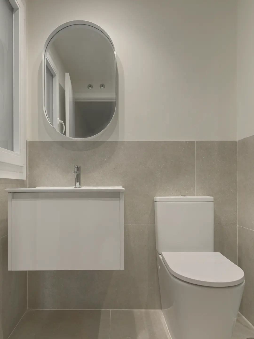Baño reformado con mueble suspendido y espejo ovalado